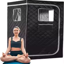Personne assise devant une cabine sauna vapeur portable noire pour une séance bien-être à domicile